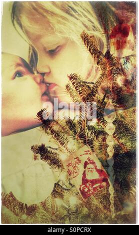 Doppelbelichtung Schwestern küssen hinter den Weihnachtsbaum Stockfoto