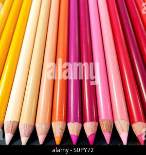 Rot, rosa und gelbe Buntstifte ausgerichtet in einer Reihe. Stockfoto