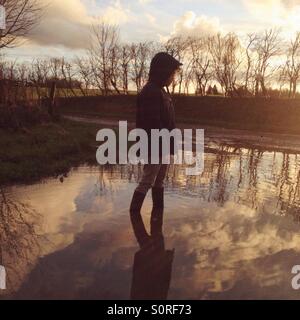 Junge stand in einer großen Pfütze, Hampshire, England. Stockfoto