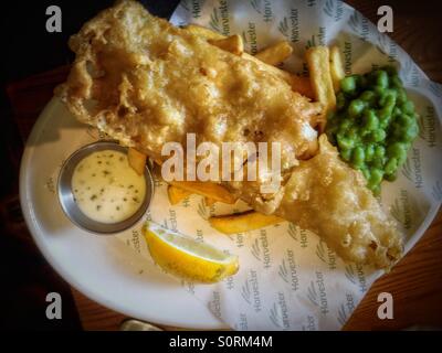 Eine Portion Fisch, Chips und Erbsenpüree aus dem lokalen Harvester Restaurant. Stockfoto