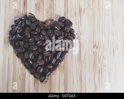 Herzform aus Kaffeebohnen auf einem Holztisch von oben gemacht Stockfoto