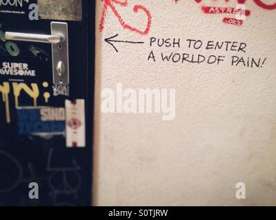 Graffiti in einer Toilette stall in einer Bar sagen Push-to-geben eine Welt voller Schmerzen Stockfoto