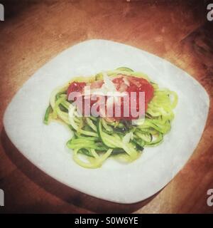 Zucchini-Spaghetti mit Tomatensauce auf einem weißen Teller garniert gekocht. Distressed bearbeiten. Stockfoto