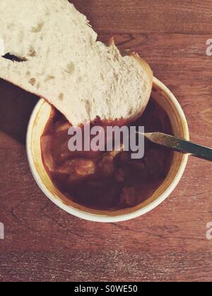 Süß-saurer Kohlsuppe mit Brot in einem Take away Behälter auf einem Holztisch Stockfoto