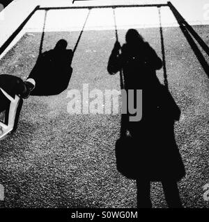 Schatten von Mutter und Kind auf Schaukel Stockfoto