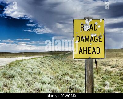 Eine Straße beschädigen vorne Zeichen voller Einschusslöcher auf einsamen Straße in Wyoming. Stockfoto