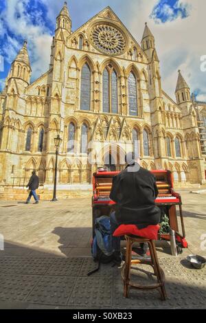 Ein Straßenmusikant Klavierspiel außerhalb York Minster in der Stadt York. Ein Klavierspieler vor einer Kathedrale. Stockfoto