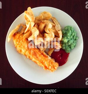 Teller mit traditionellen englischen Fish And Chips mit Erbsenpüree und Tomatensauce. Stockfoto