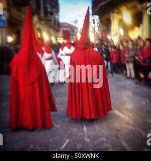 Büßer tragen rote Umhänge und Spitzen Kapuzen während der Karwoche in Astorga, Maragateria, Leon, Spanien Stockfoto