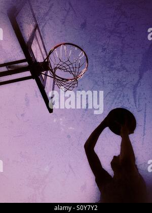 Silhouette von einem Teenager schießen einen Basketball im Freien. Lila und Magenta Farben. Stockfoto