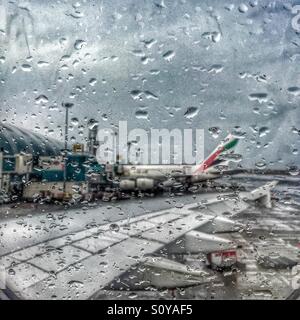 Geparkten Emirates Airline Flugzeug gesehen durch das regnerische Flugzeug Fenster am Dubai International Airport Stockfoto