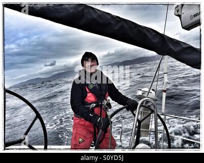 Lächelnde Skipper an der Spitze einer Segelyacht in dunklen und stürmischen Wetter Stockfoto