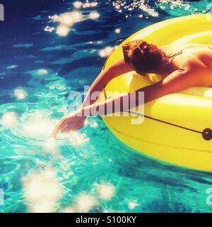 Frau Entspannung im Pool an einem heißen sonnigen Tag. Stockfoto