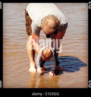 Großvater und Enkelin spielen im Meer Stockfoto