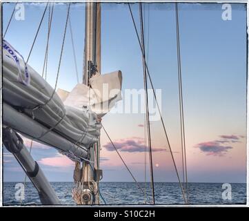 Vollmond über den Horizont steigt auf hoher See, von einer Segelyacht Stockfoto