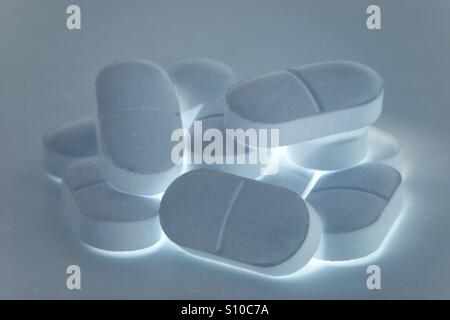 Ein Haufen von glühenden Pillen, Tabletten oder Drogen auf einem weißen Hintergrund. Leuchtende schmerzstillende Tabletten. Stockfoto