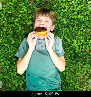 Junge Essen einen Donut, Donut im Park Stockfoto