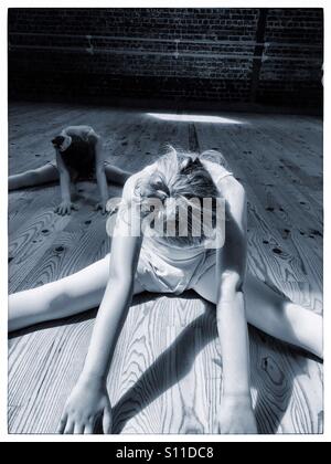 Mädchen 8-10 Jahre Ballett stretching-Übungen auf einem Holzfußboden in einem Ballettstudio Stockfoto
