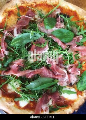 Hausgemachte Pizza, Parmaschinken, Basilikum und Rucola. Stockfoto