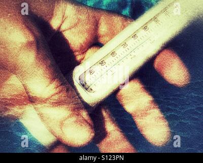 Überprüfung der Wassertemperatur ein Schwimmbad mit einem Wasserthermometer Stockfoto