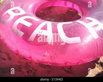 Rosa aufblasbaren Ring mit dem Wort "Strand" drauf gelegt am Strand Stockfoto