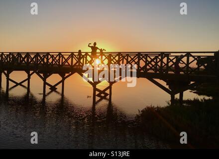 Sonnenuntergang auf der Holzbrücke über das Naturschutzgebiet Ria Formosa in Quinta Do Lago in Portugal. Stockfoto