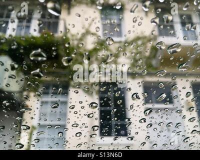 Regentropfen auf der Windschutzscheibe Blick auf Gebäude mit schleichenden Rebe Stockfoto