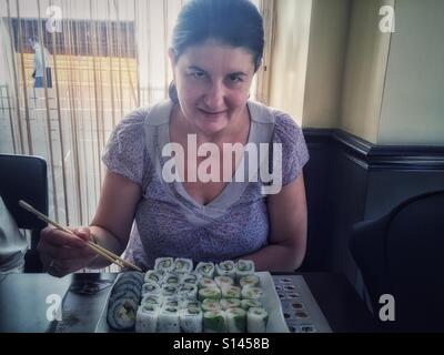 Reife Frau Sushi-Essen im restaurant Stockfoto