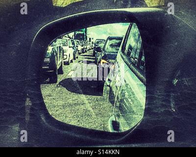 Mit dem Auto anreisen. Reflexion im Außenspiegel an Schwerlastverkehr an einem Stand noch auf der A303 in der Nähe von Stonehenge. Stockfoto