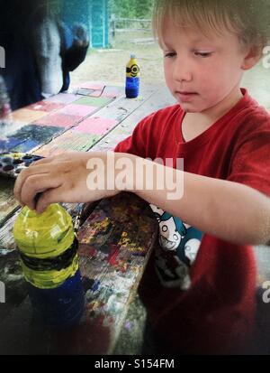 Ein Junge malt eine Plastikflasche, ein Handwerk zu machen. Stockfoto