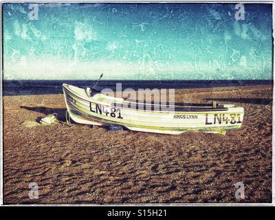 Ein einsames Boot liegt am Strand in Blakeney National Nature Reserve in der Nähe von Cley-Next-the-Sea in Norfolk, England. Das Meer am Horizont ist die Nordsee. Bildnachweis - © COLIN HOSKINS. Stockfoto