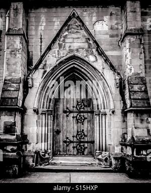 Bogenförmiger Eingang im gotischen Stil zur mittelalterlichen Kirche mit Holztür und schmiedeeisernen Scharnieren, Schottland, Großbritannien Stockfoto