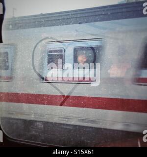 Herzen im Staub auf einem Zugfenster mit der Reflexion des Gesicht einer Frau gezeichnet Stockfoto