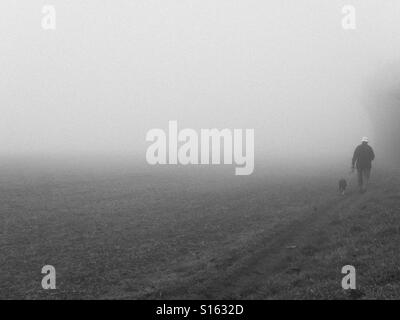 Mann zu Fuß Hund im Nebel in England Stockfoto