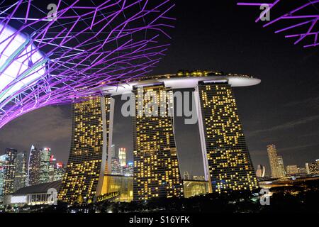 Singapore Marina Bay Sands Hotel in der Nacht, mit Riesen floralen Skulpturen von Gardens By The Bay, Marina Bay, daneben. Stockfoto