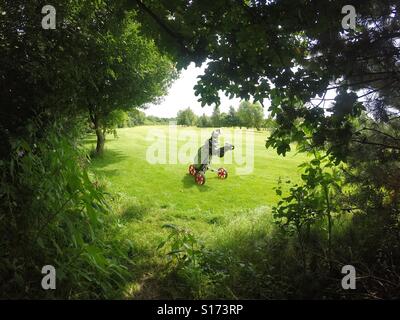 Golf Clubs In ein Cartbag auf eine Golf-Trolley In der Fahrrinne von den Bäumen und In der rauen auf einem Golfplatz jetzt Atem!!! Stockfoto