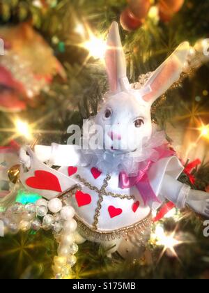 Ein weißen Kaninchen gekleidet wie ein Hofnarr eine schöne Weihnachtsverzierung auf einem funkelnden bunt geschmückten Weihnachtsbaum ist Stockfoto