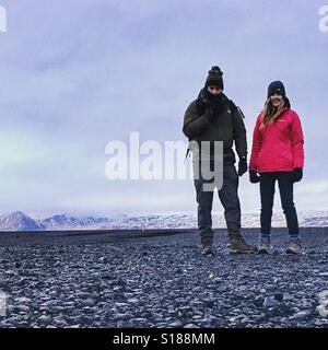 Zwei Personen am schwarzen Strand in Island mit Schnee bedeckt Berge im Hintergrund. Platz für text Stockfoto