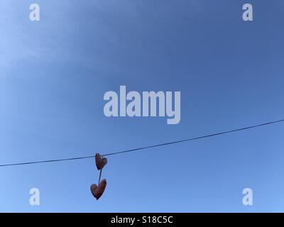 Herzförmige Luftballons hängen an einem Draht über eine Straße. Stockfoto