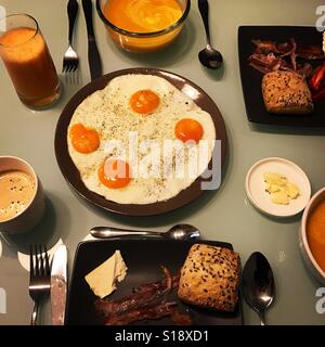 Frühstückstisch. Eiern, Speck, Kaffee, frisch gepresster Orangensaft, Creme Karottensuppe. Brunch für zwei Stockfoto