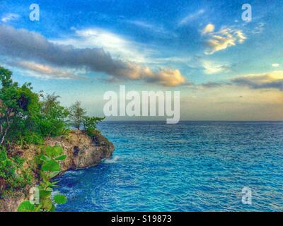 Blick auf das ruhige Meer und Klippen bei Sonnenuntergang am Westende, Negril, Jamaika Stockfoto