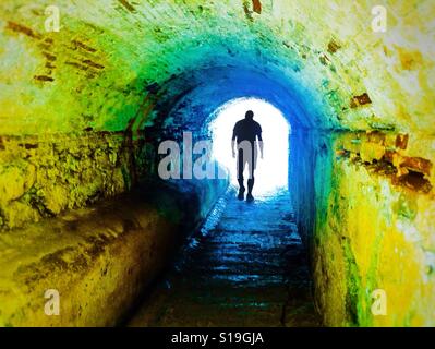 Anonyme Silhouette eines Mannes zu Fuß durch eine dunkle Unterführung symbolisiert Licht am Ende eines Tunnels Stockfoto