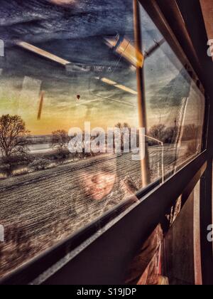 Reflexion einer Frau auf einem Zugfenster, Natur-Ansicht und einen Heißluftballon außerhalb Stockfoto