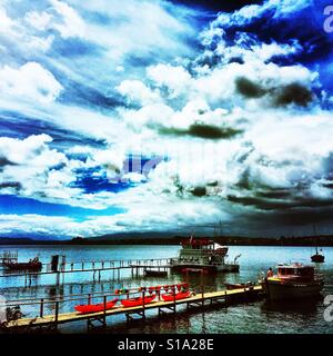 Eine große Wolke gefüllten Stimmungsvoller Himmel über dem Lago Llanquihue mit Boote, Kanus und Stege in den Vordergrund, Puerto Varas, Südchile Stockfoto