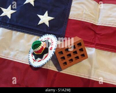 Einzelne Lehmziegel und Mexican Hat auf Stars And Stripes Flagge von Amerika. Donald Trump angekündigt, um eine Mauer an der Grenze zu errichten. Stockfoto