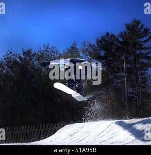 Snowboarder in die Luft, die aus einem Sprung Stockfoto