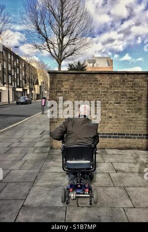 Mann im Rollstuhl Mobilität, mit Blick auf eine Backsteinmauer Stockfoto