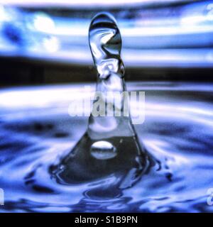 Close-up iPhone Foto mit einem Makro-Objektiv-Anhang eines Wassertropfens Spritzwasser in einer Lache des Wassers. Stockfoto