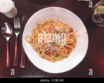 Eine Schüssel Spaghetti Bolognese auf einem Tisch, mit Besteck auf der Seite von oben gesehen. Stockfoto