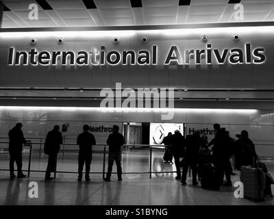 Menschen warten in der internationalen Ankunftshalle am Flughafen London Heathrow Stockfoto